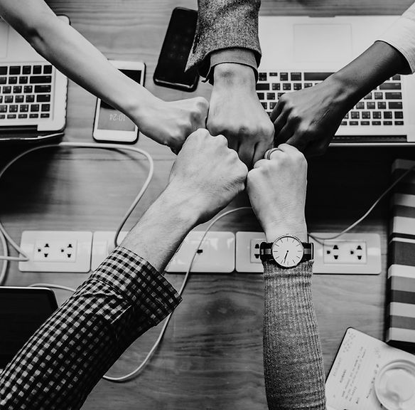 Colleagues bumping fists over a desk of laptops