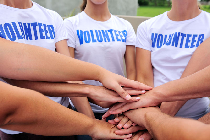 Volunteers in matching shirts stacking their hands
