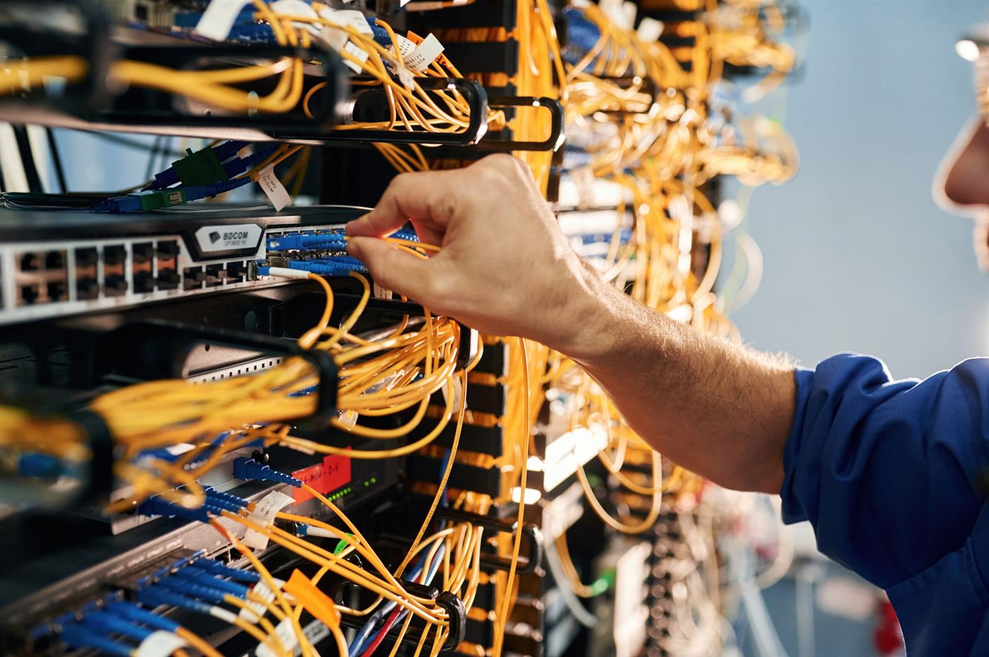 A technician connecting patch cables in a network rack